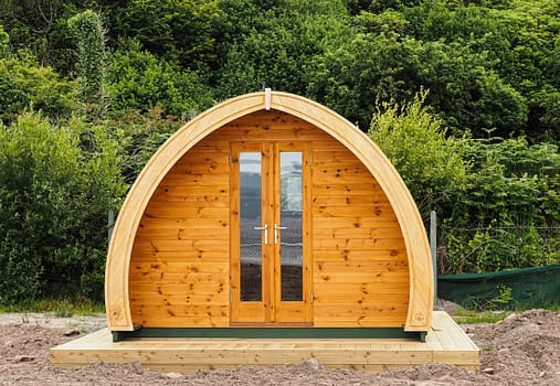 pexels-photo-6492443 A modern wooden cabin with arched design amidst green foliage. Perfect getaway.